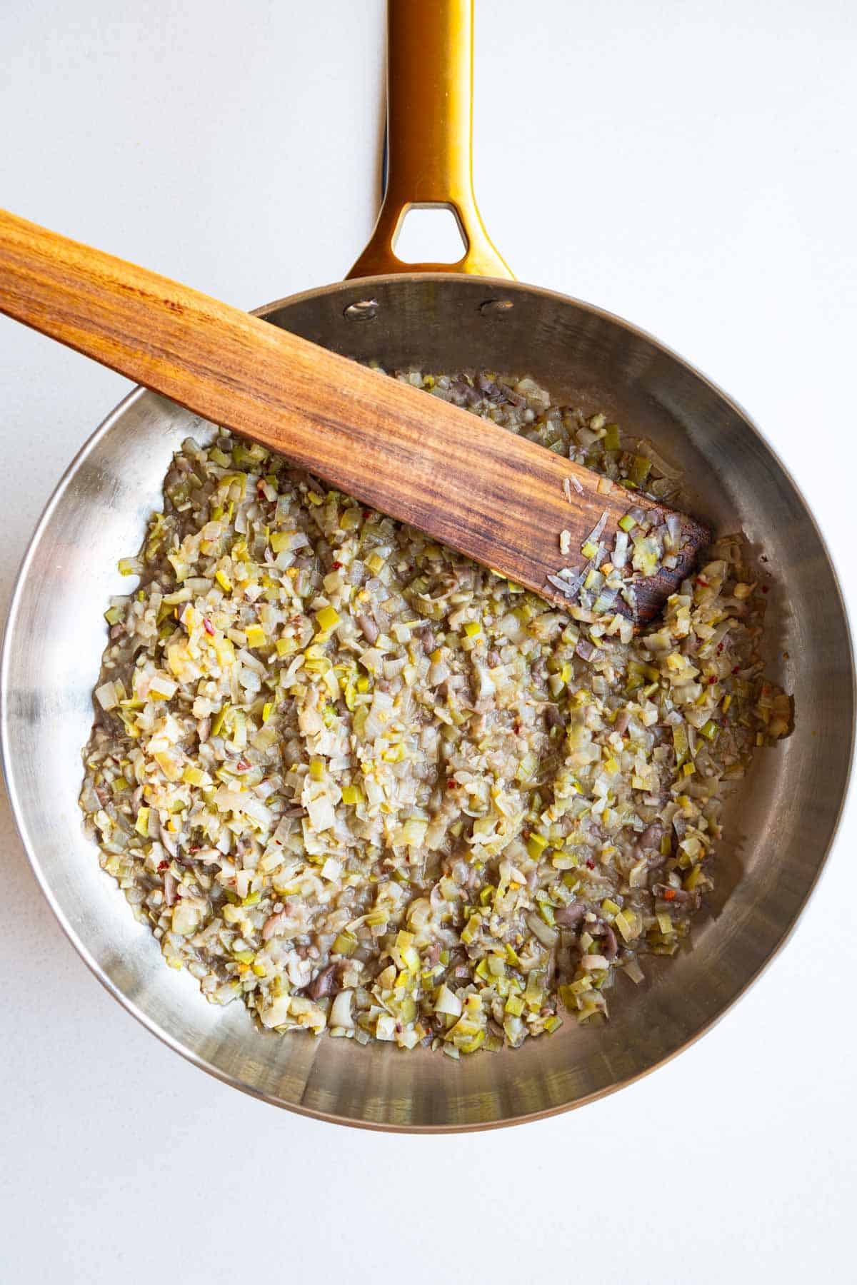 Cooked aromatics in a saucepan with mashed beans.