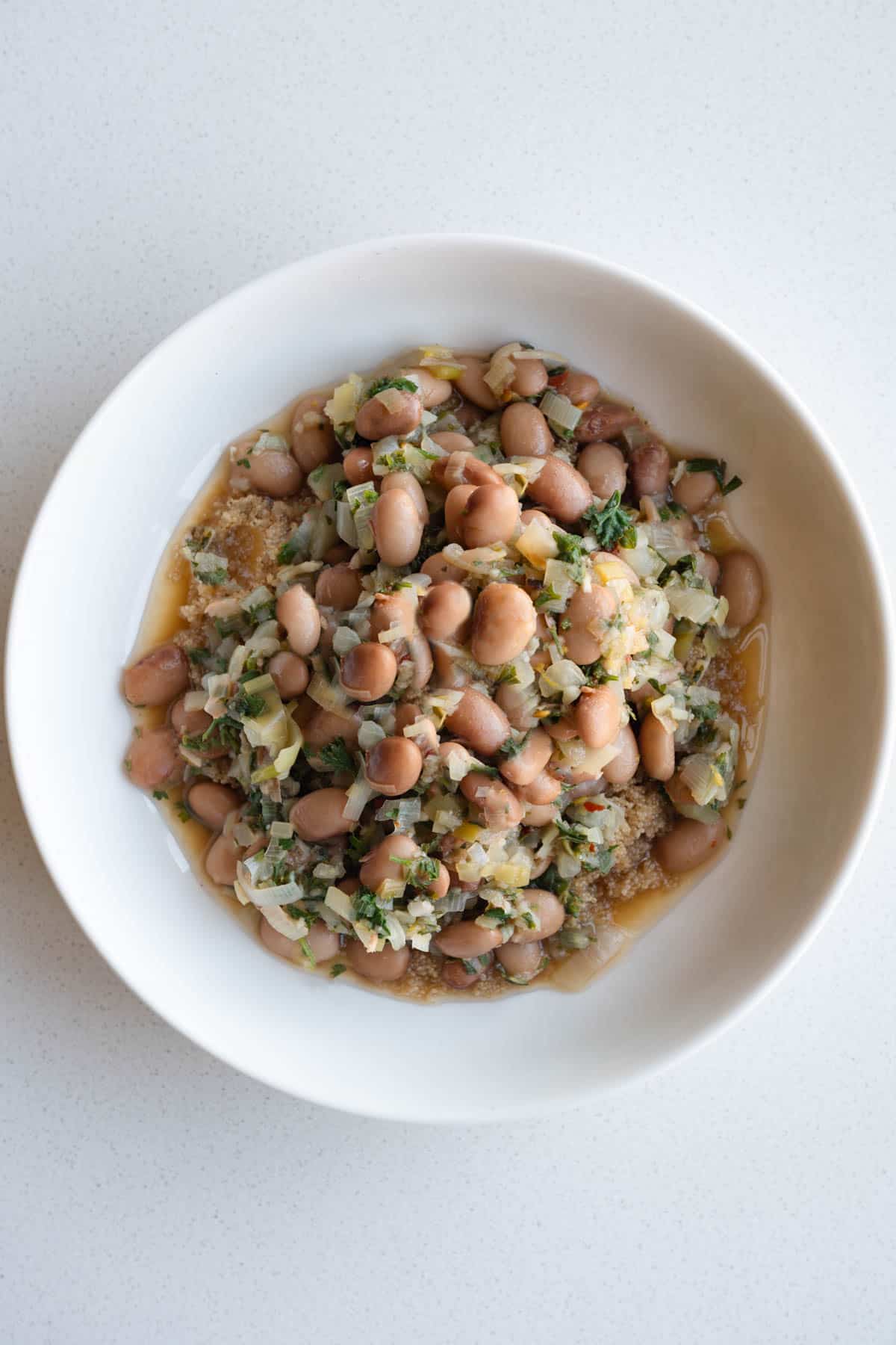 Brothy pinto beans with lemon, leeks, and fresh herbs in a bowl.
