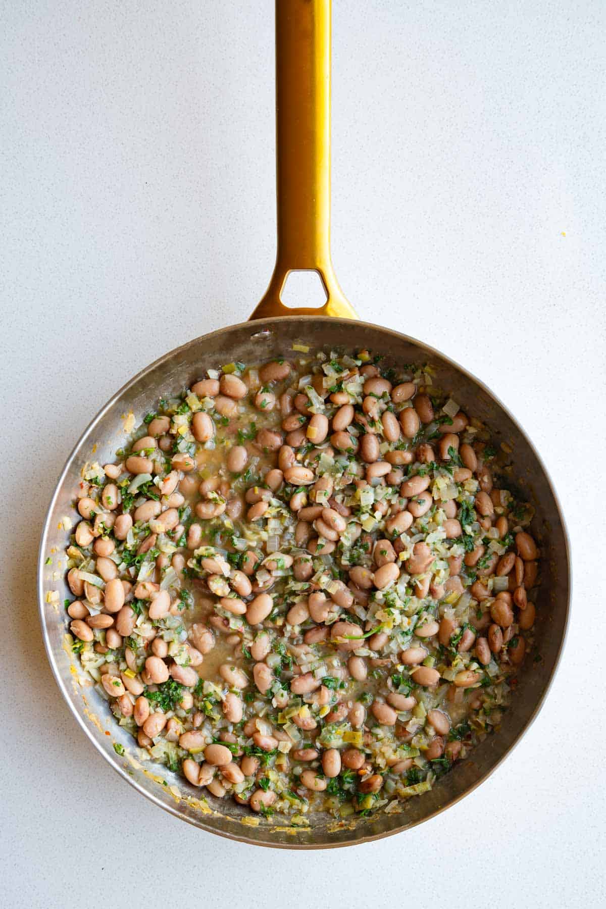 Brothy pinto beans with leeks and lemon in a saucepan.