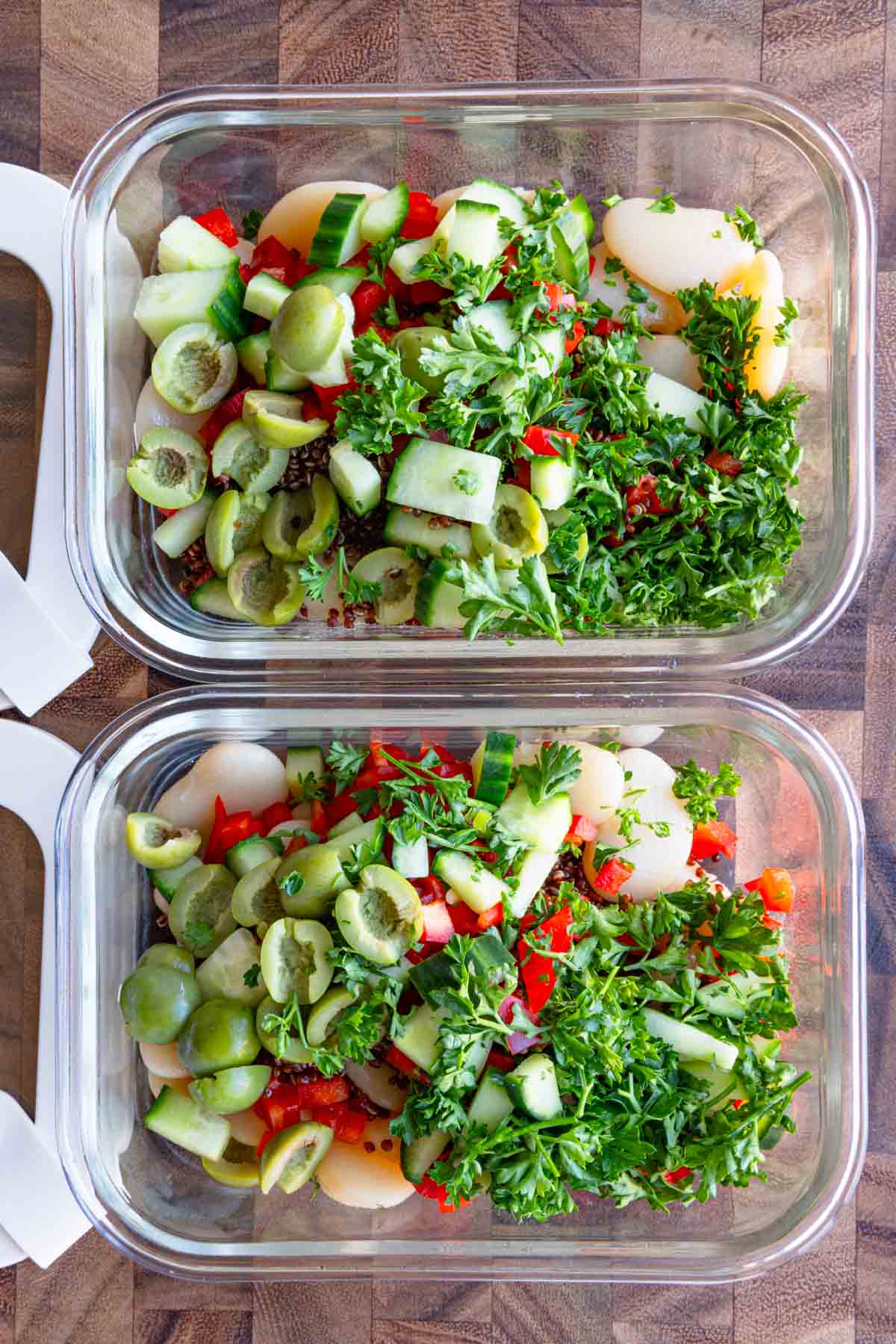 Butter beans, red quinoa, chopped herbs, scallions, and bell pepper in a two meal prep containers.