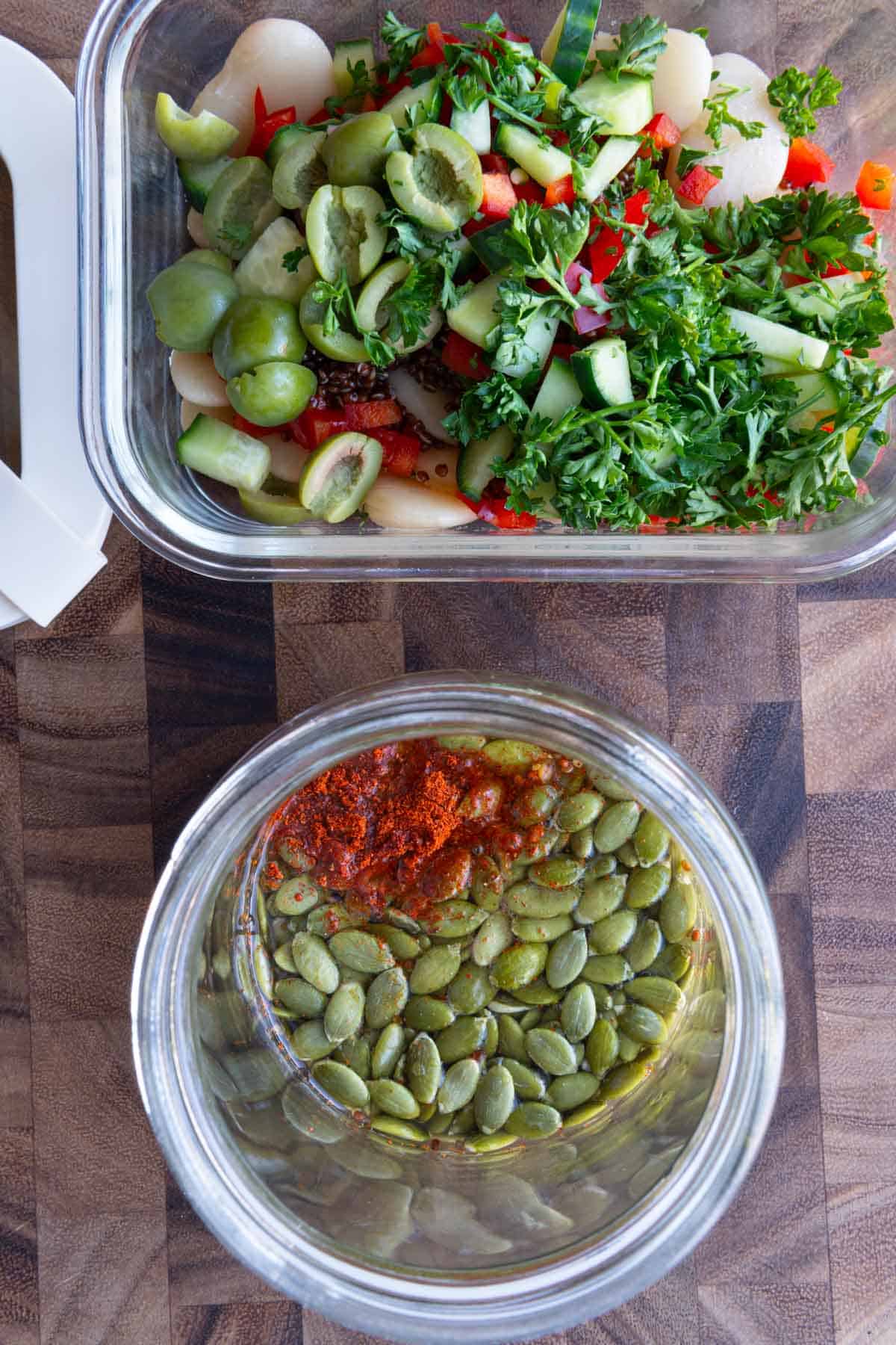 Ingredients for white bean quinoa salad in a meal prep container and pumpkin seed dressing ingredients in a glass jar.