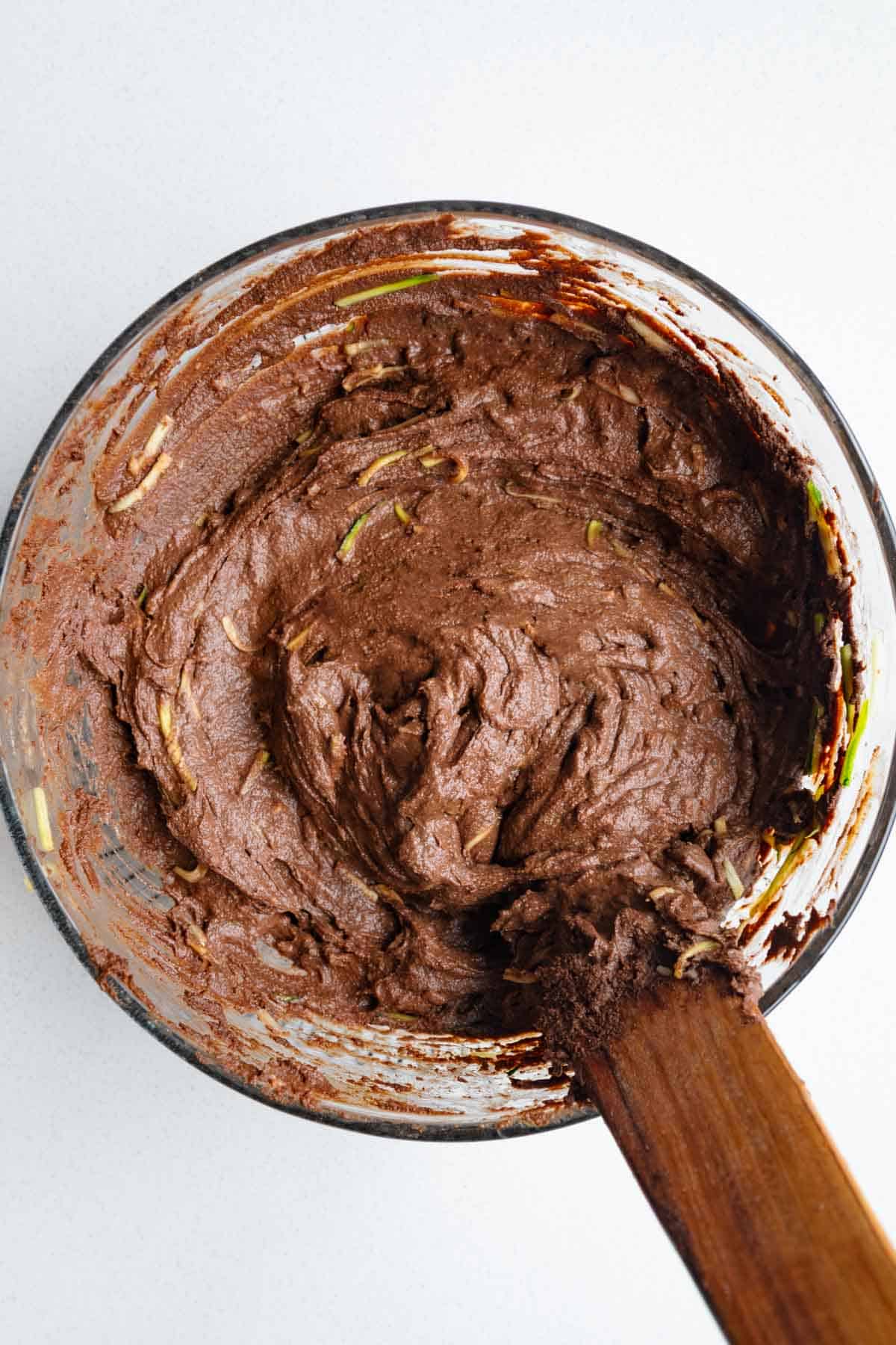 Chocolate cake batter in a glass bowl with zucchini.