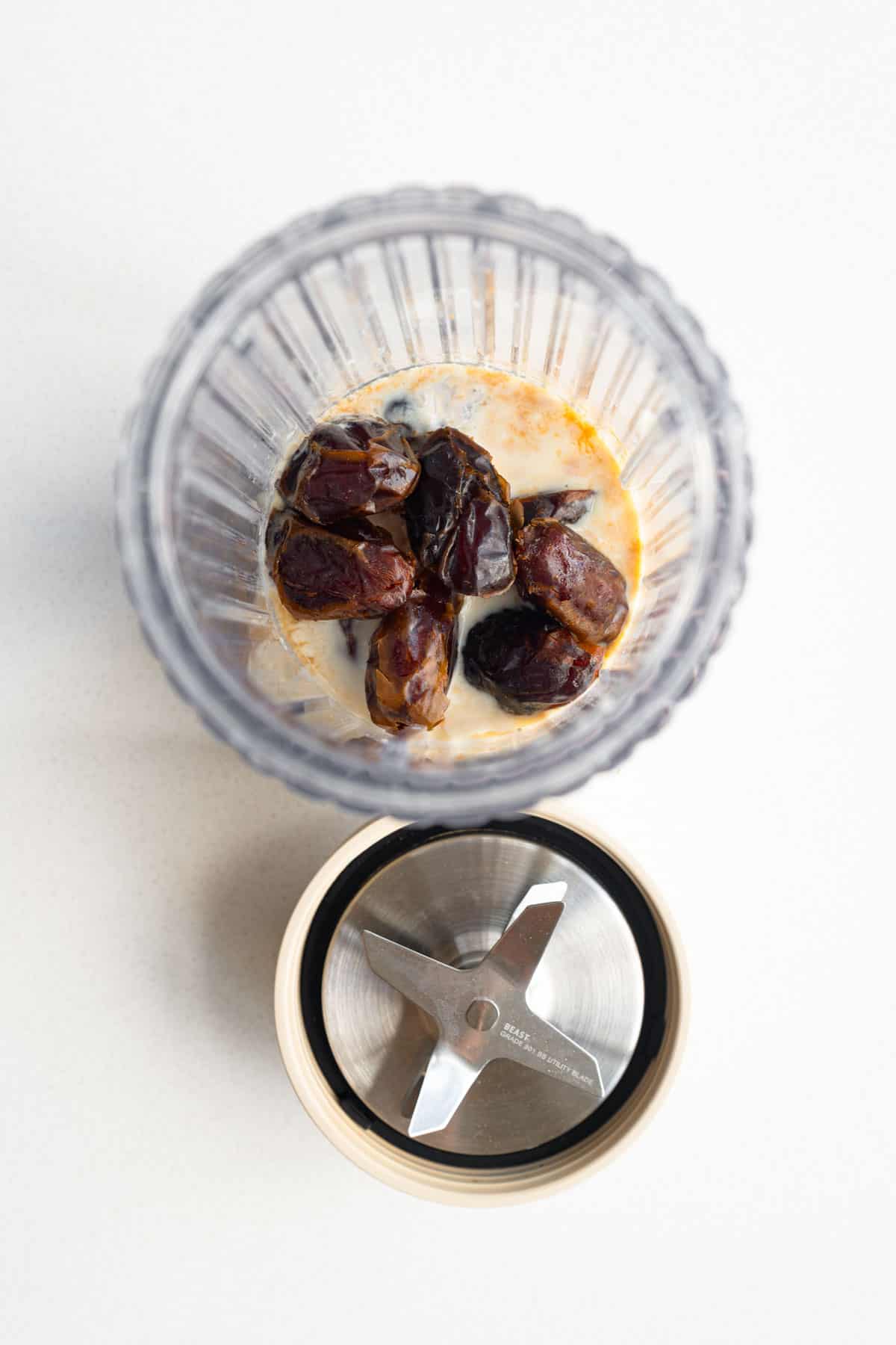Medjool dates, nondairy milk, vanilla extract, and silken tofu in the canister of a blender.