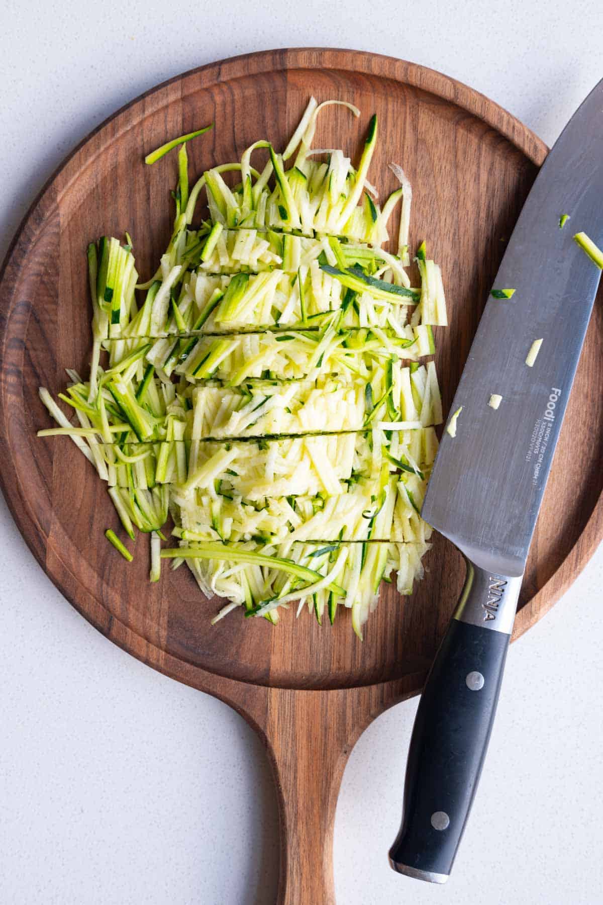 Julienned and chopped zucchini on a cutting board.