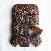 Healthy zucchini chocolate cake cut into squares on white parchment paper.