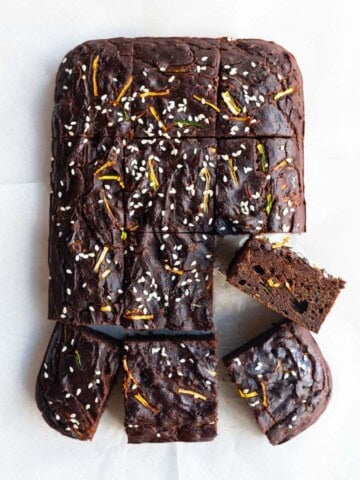 Healthy zucchini chocolate cake cut into squares on white parchment paper.