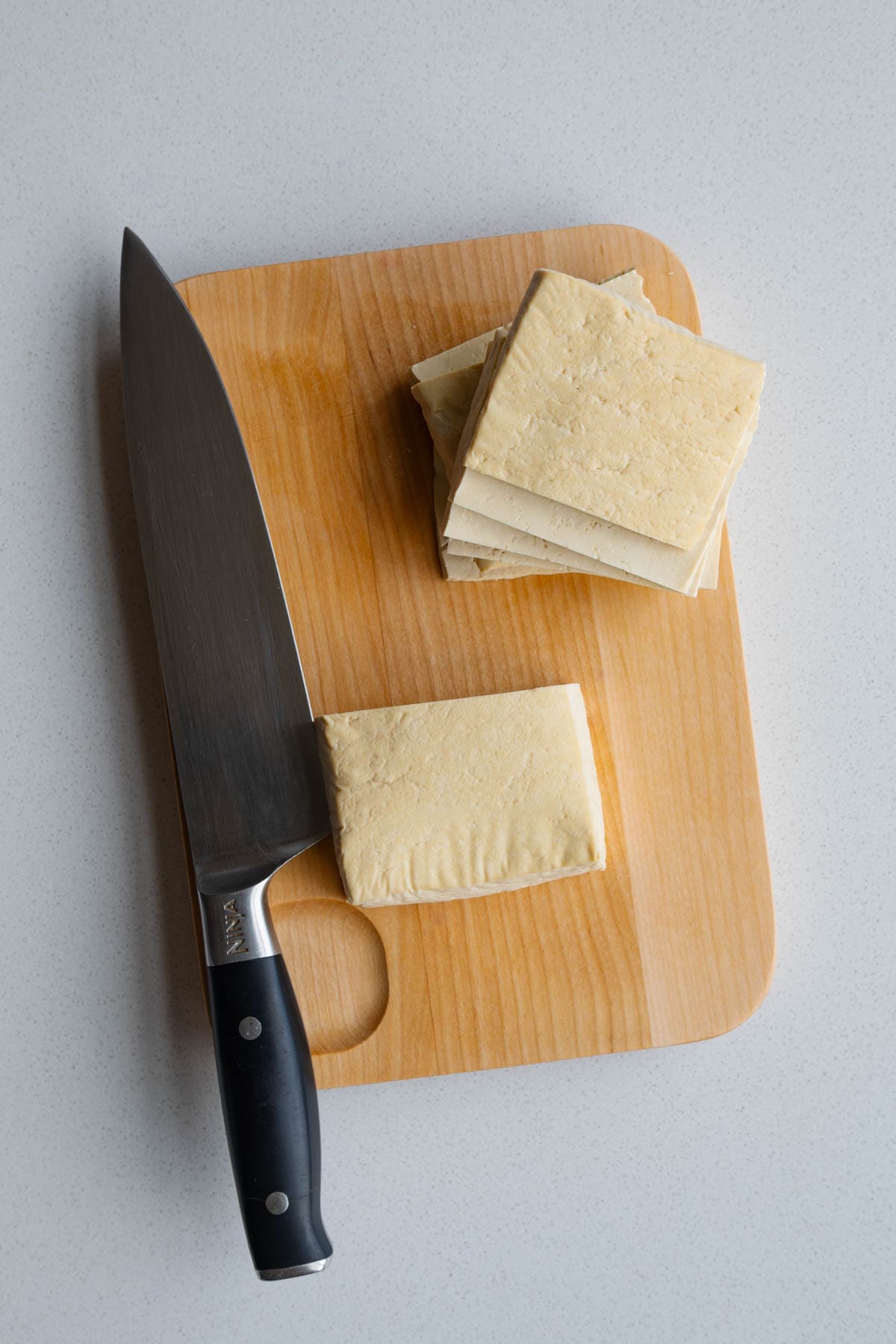 Thinly sliced tofu on a cutting board.