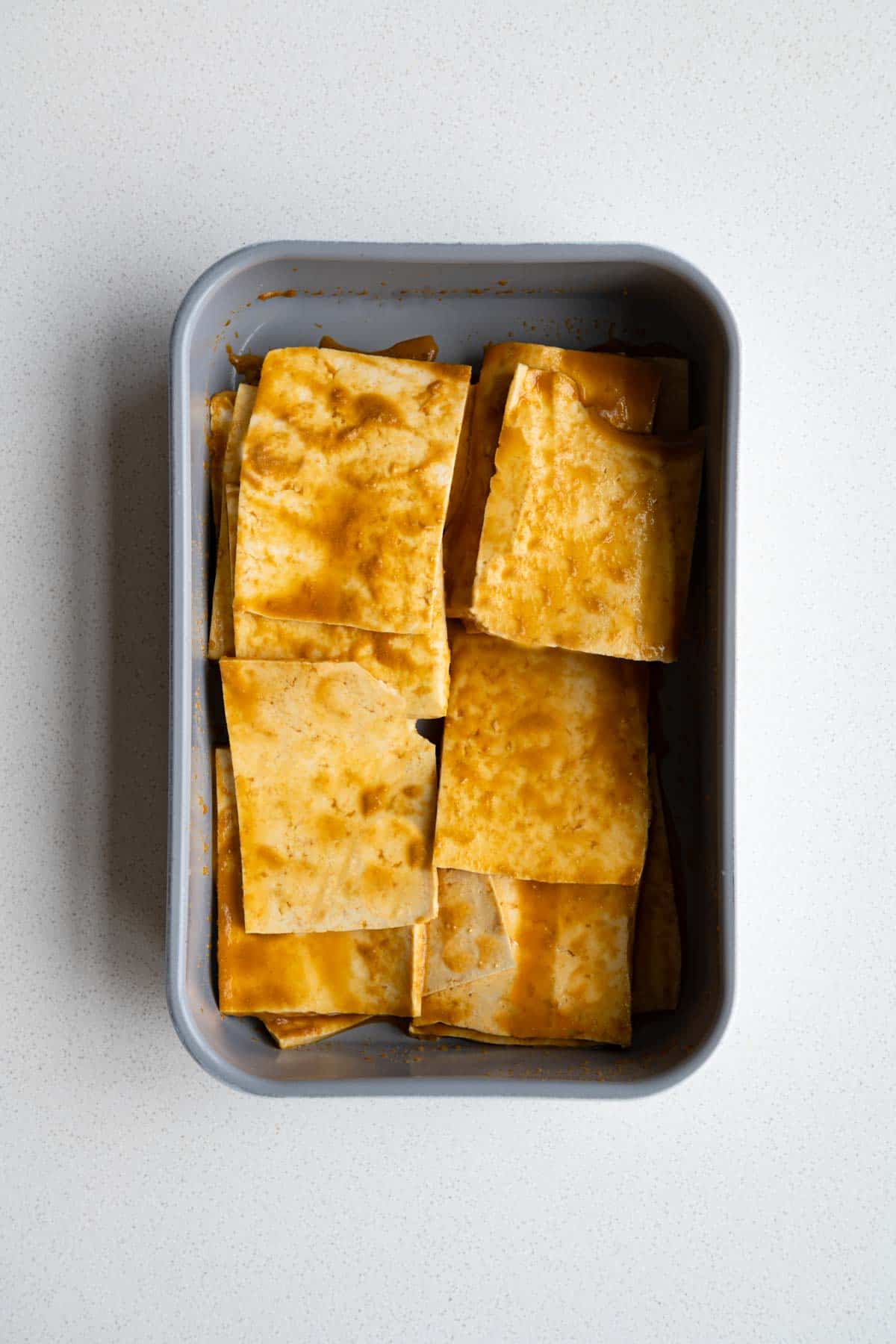 Sliced tofu marinating in a baking dish.