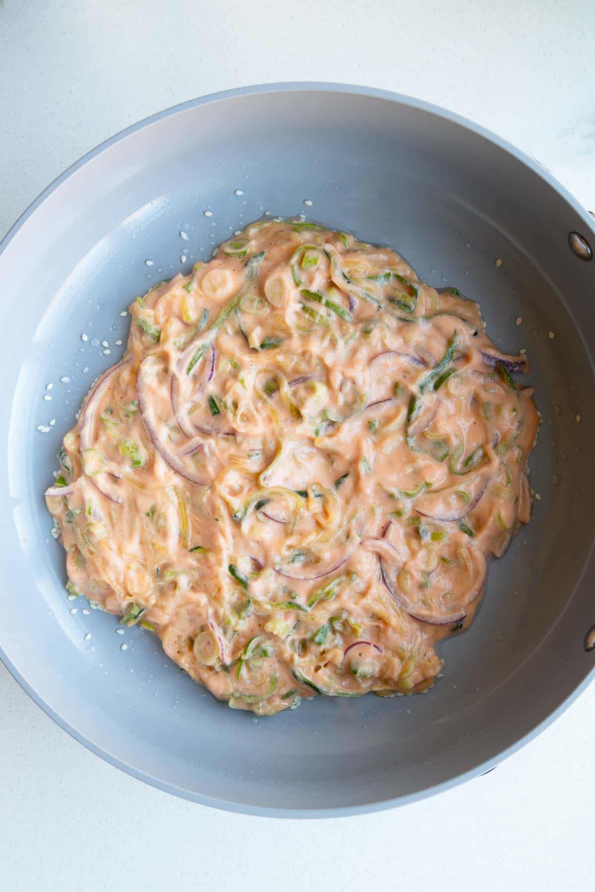 Zucchini pancaked made with red lentils in a skillet.