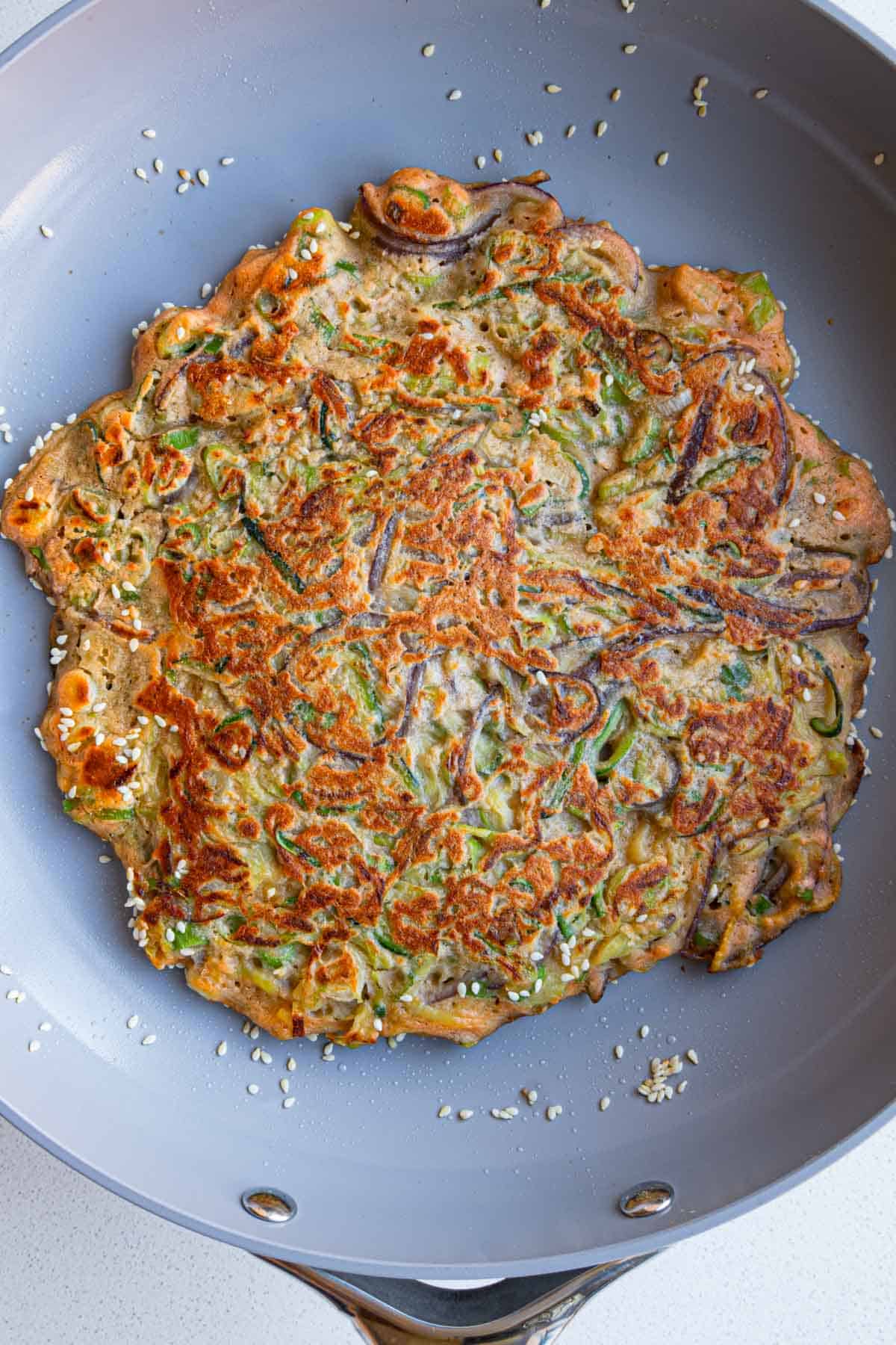 Zucchini pancakes made with red lentils in a skillet.