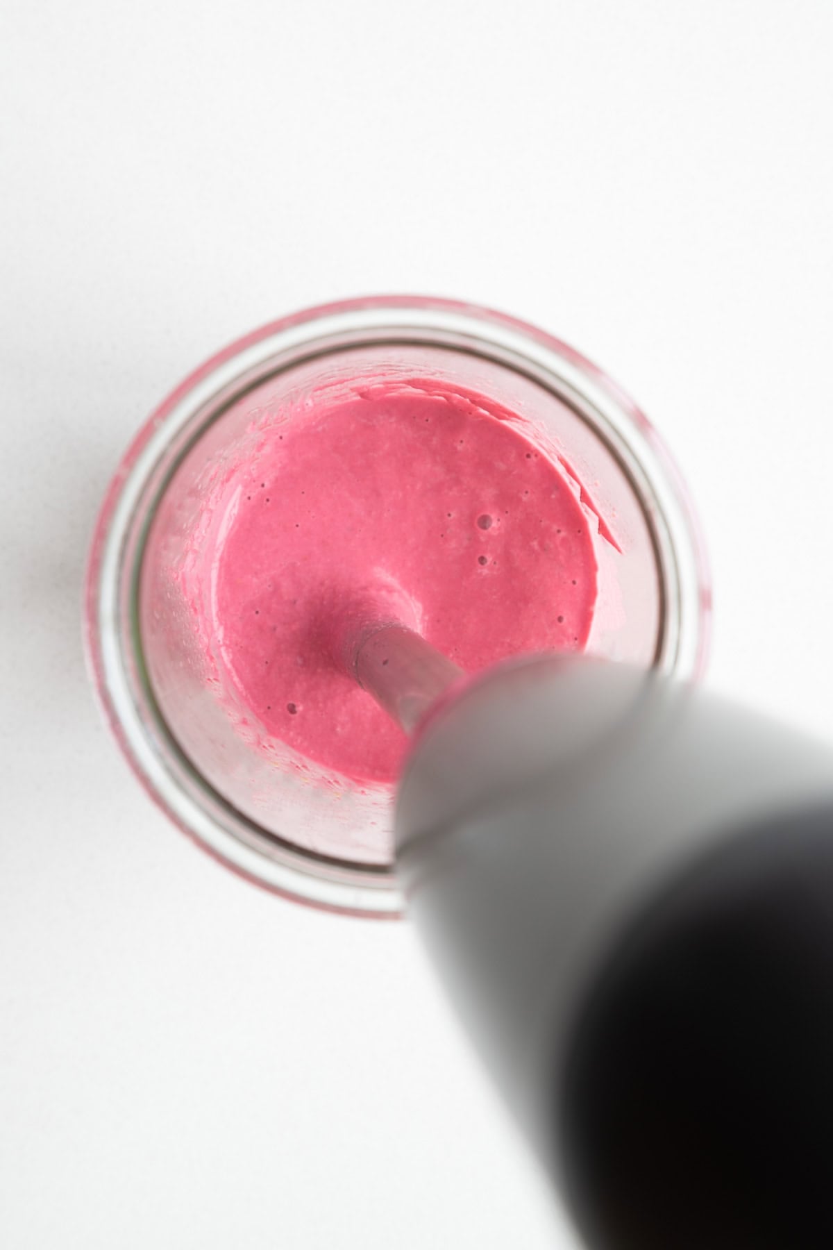 Blending beets, lemon juice, soaked walnuts, garlic, and miso with an immersion blender in a jar.