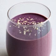 Blueberry cocoa smoothie in a glass topped with hemp hearts.