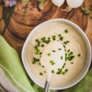 Cauliflower cream in a bowl topped with chopped chives.