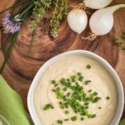 Cauliflower cream in a bowl topped with chopped chives.