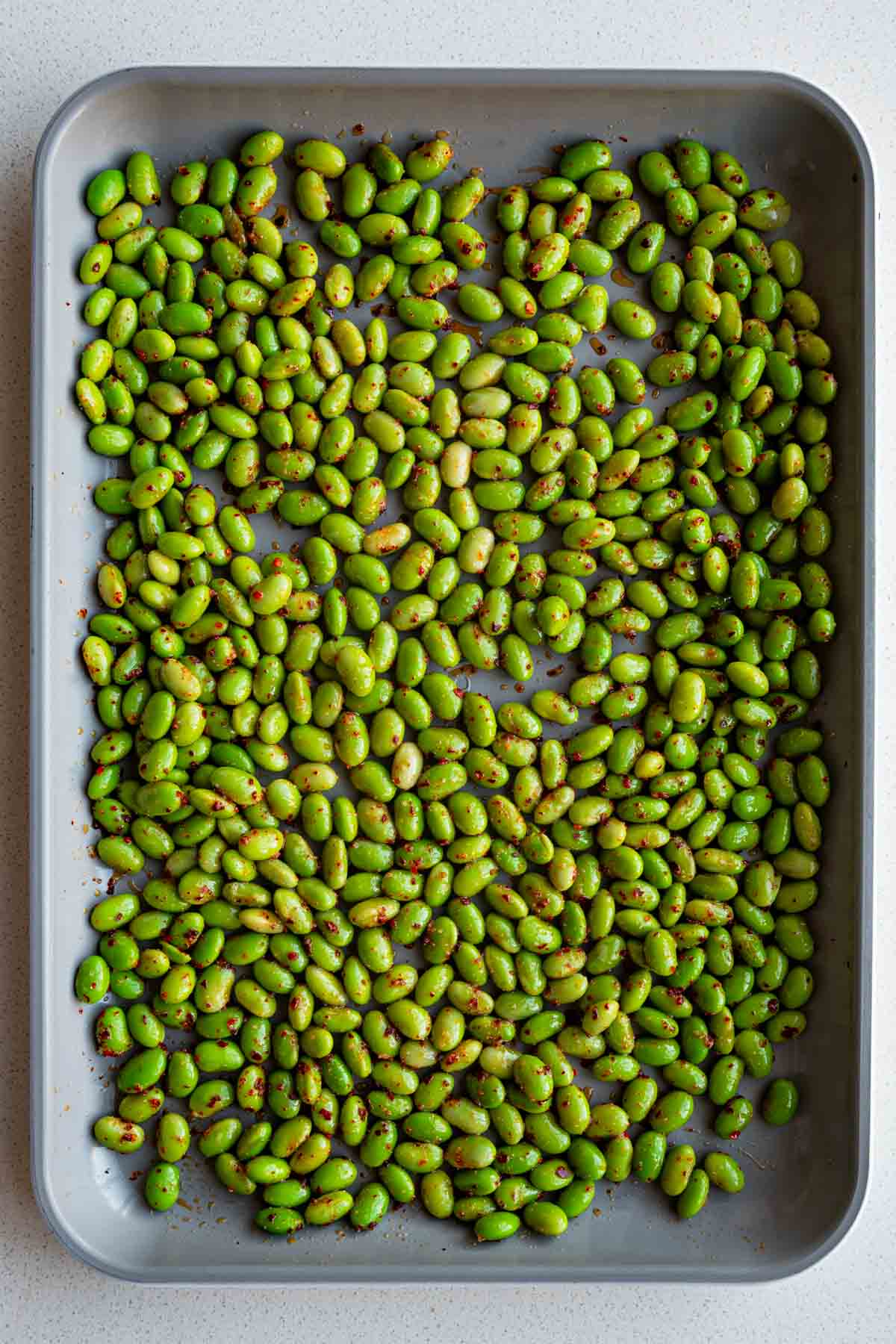 Seasoned edamame on a baking sheet.