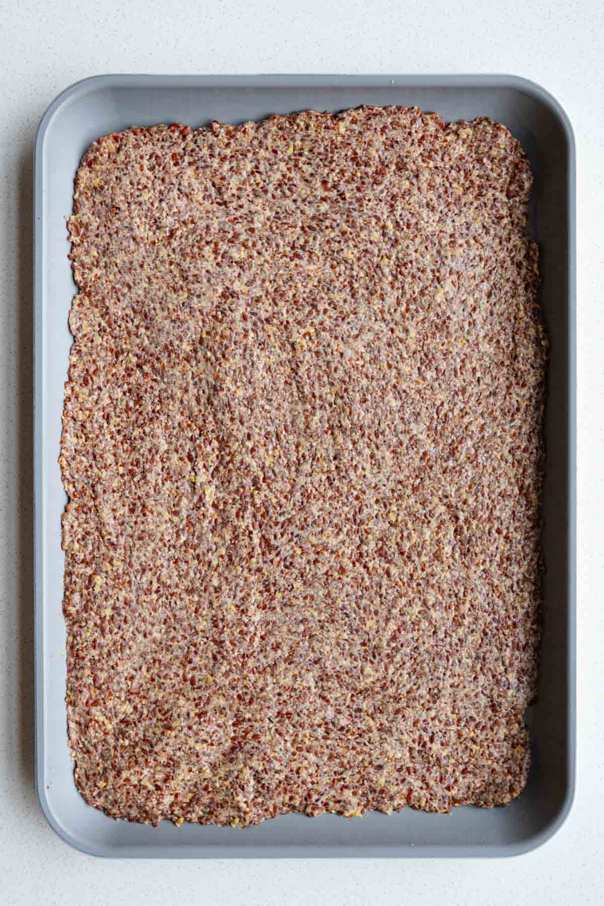 Ground flaxseed cracker dough spread onto a nonstick baking sheet.