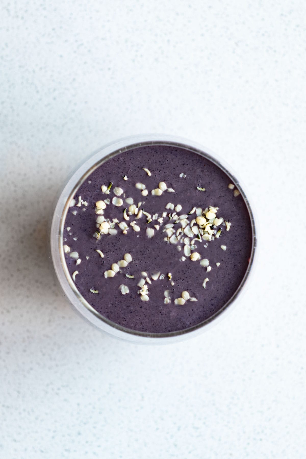 Blueberry cocoa smoothie in a glass topped with hemp hearts.