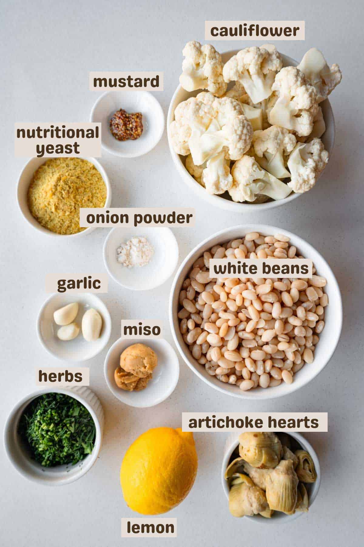 Cauliflower florets, lemon, artichoke hearts, fresh herbs, miso, garlic, onion powder, nutritional yeast, white beans, and mustard.