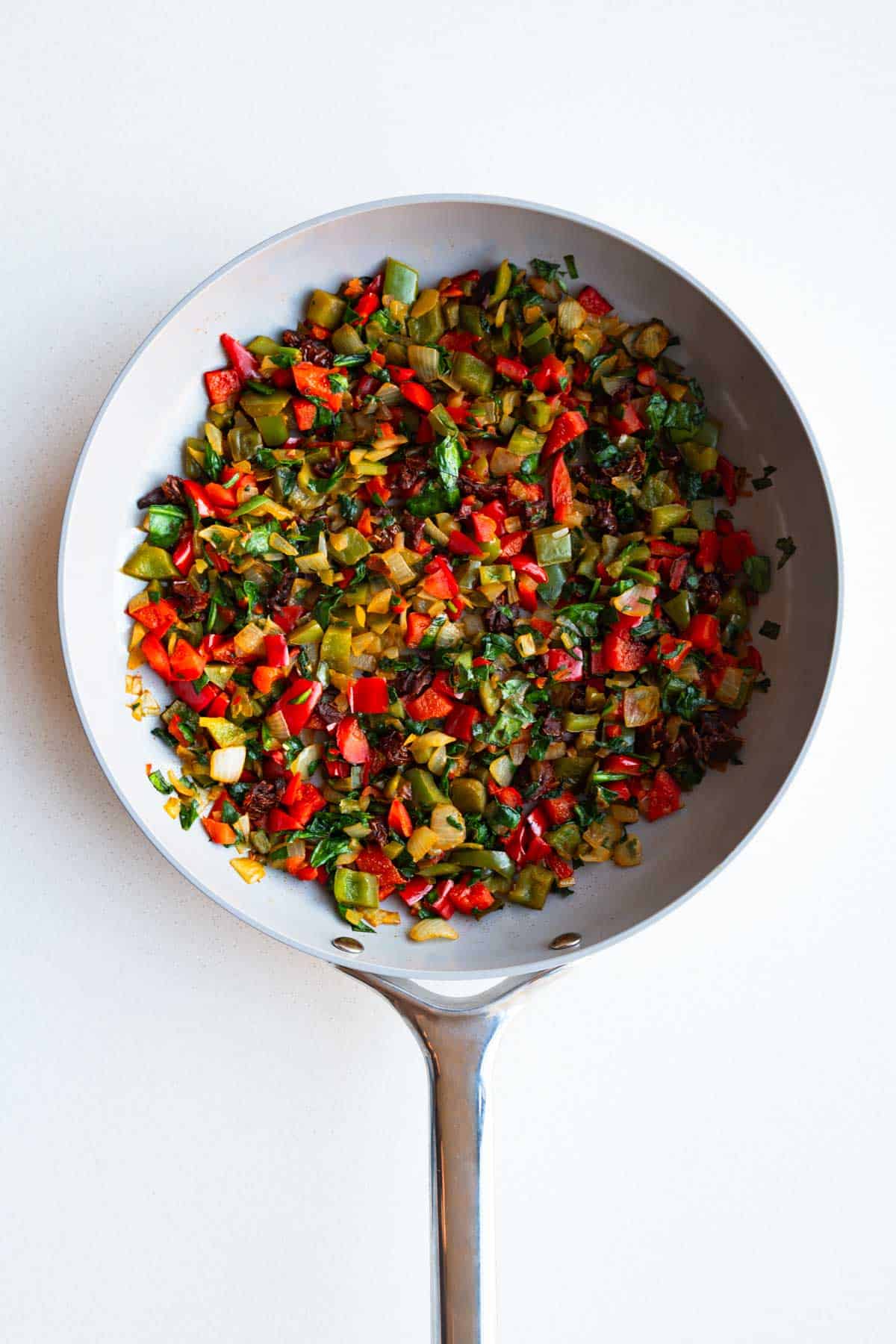 Chopped bell peppers, onion, and spinach in cooked a saucepan.
