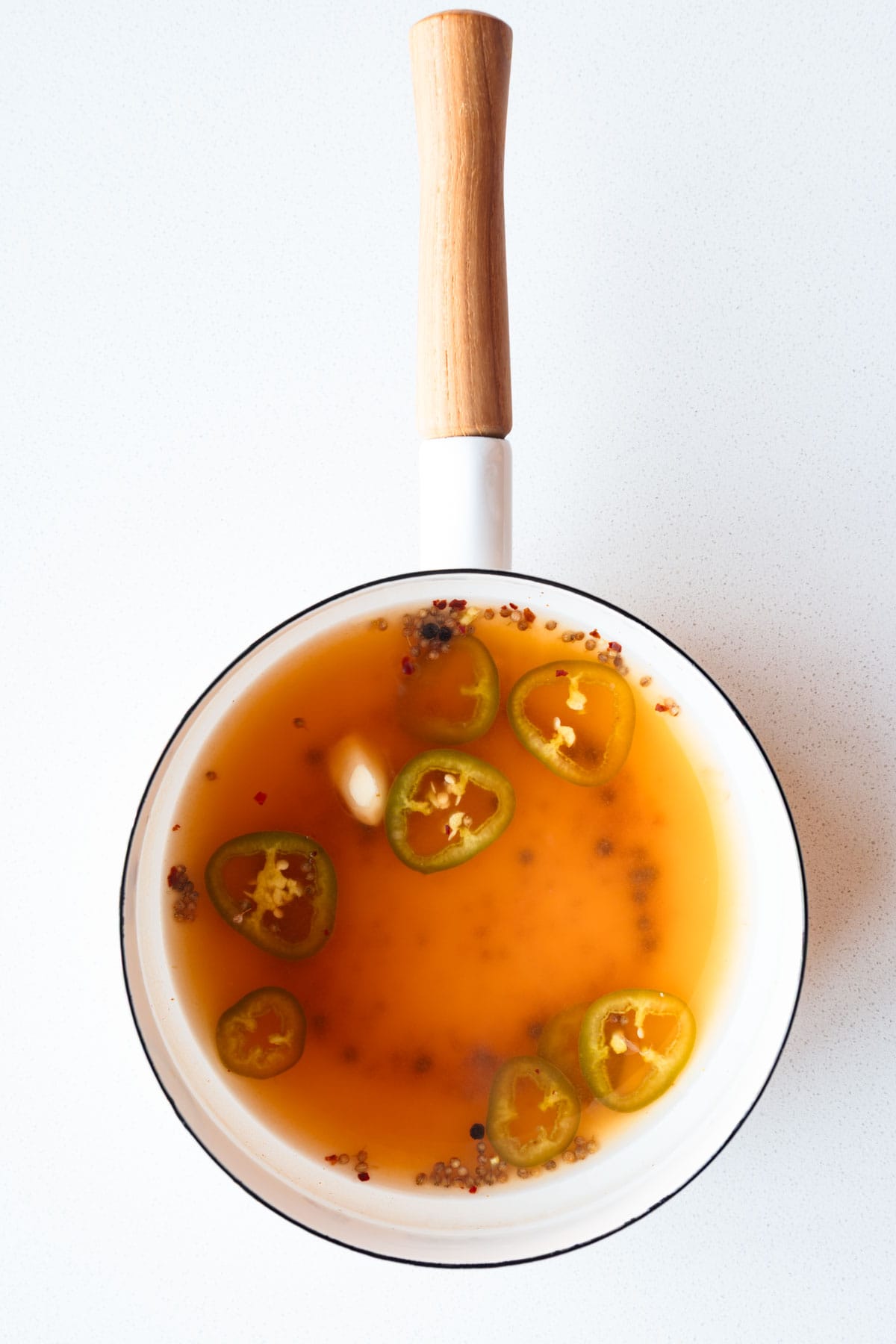 Lime juice, garlic, cumin seeds, black peppercorns, crushed red pepper, water, and apple cider vinegar in a saucepan.