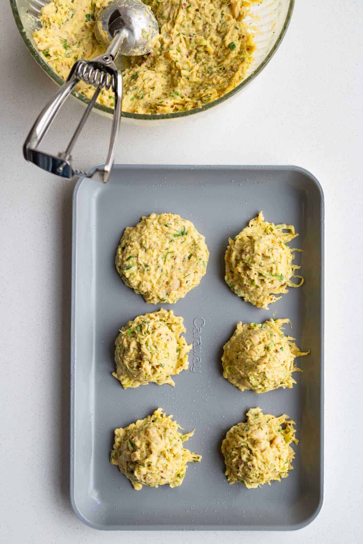 Batter for fritters scooped onto a baking sheet.