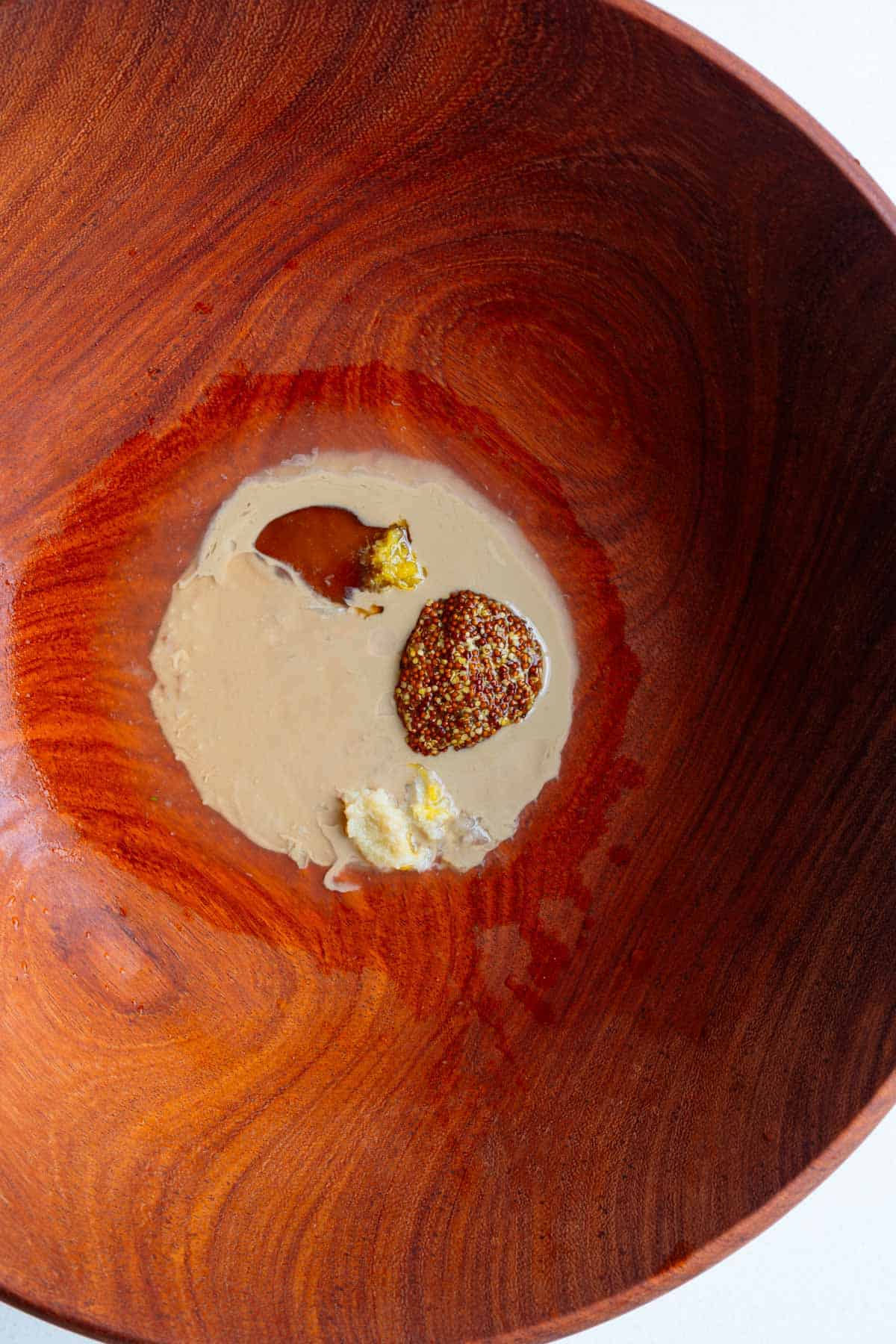 Tahini dressing ingredients in a wooden bowl.