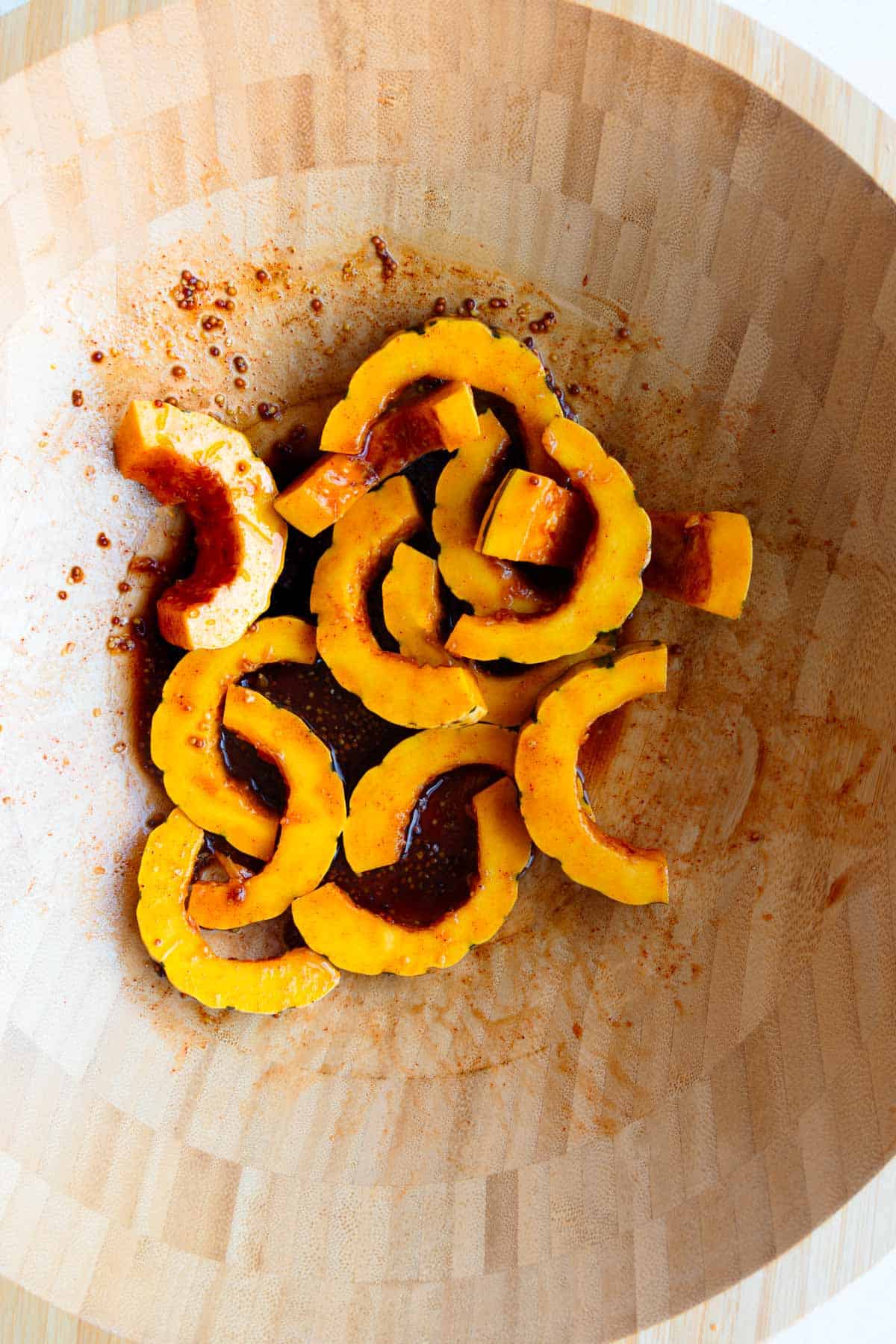 Oil-free marinade in a wooden bowl with sliced squash.