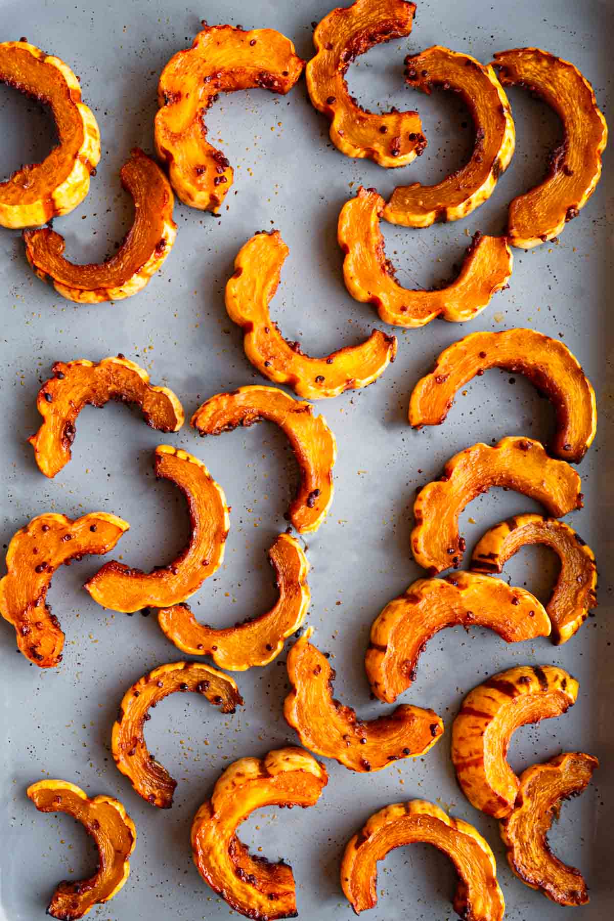 Roasted delicata squash on a baking sheet.