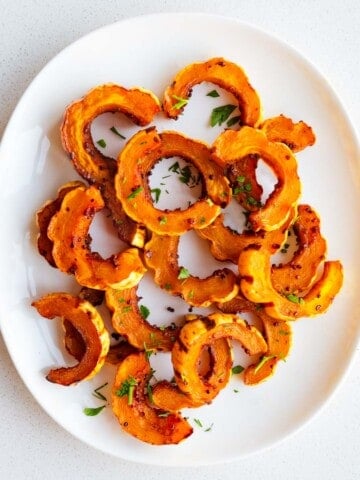 Roasted delicata squash on a white plate.