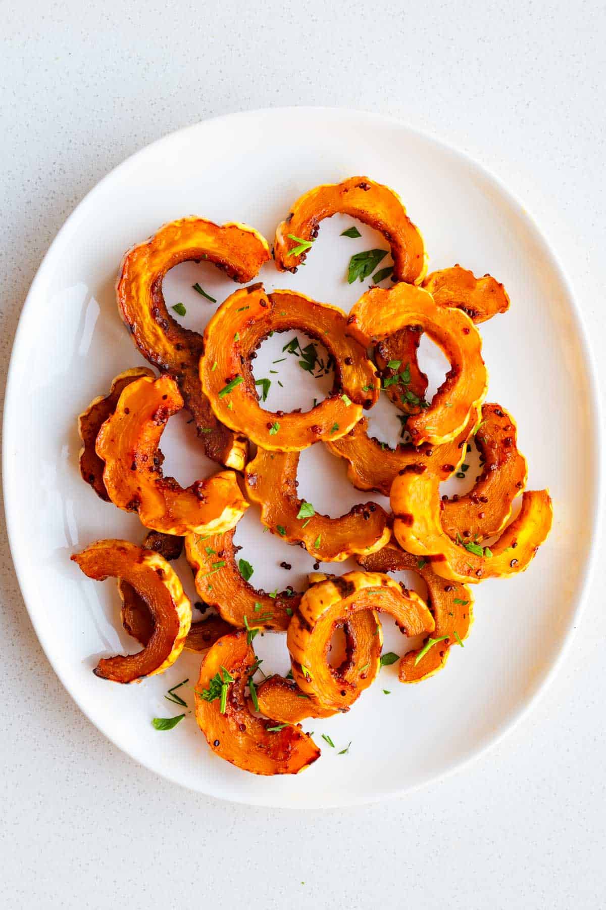 Roasted delicata squash on a white plate.