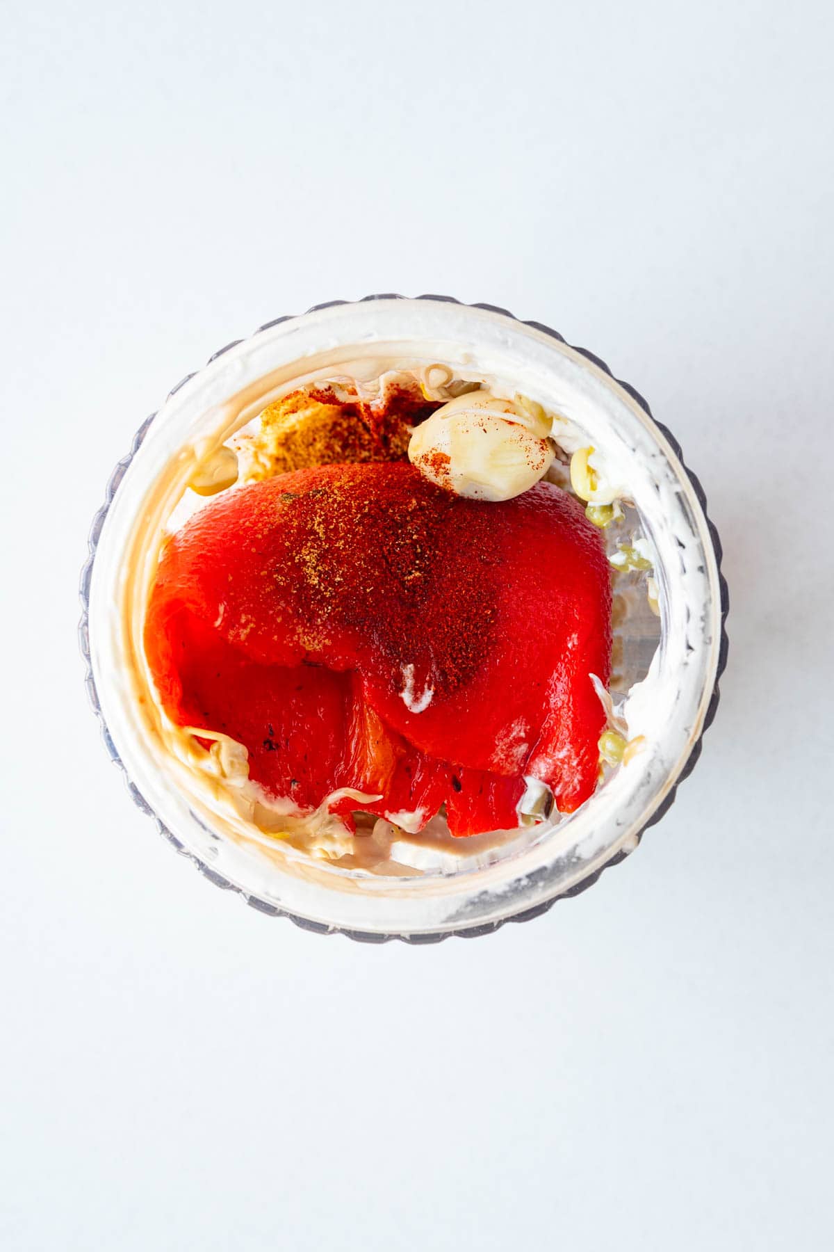 Roasted red bell pepper, tahini, lemon juice, garlic, sprouted legumes, seasoning, and ice water in a blender.