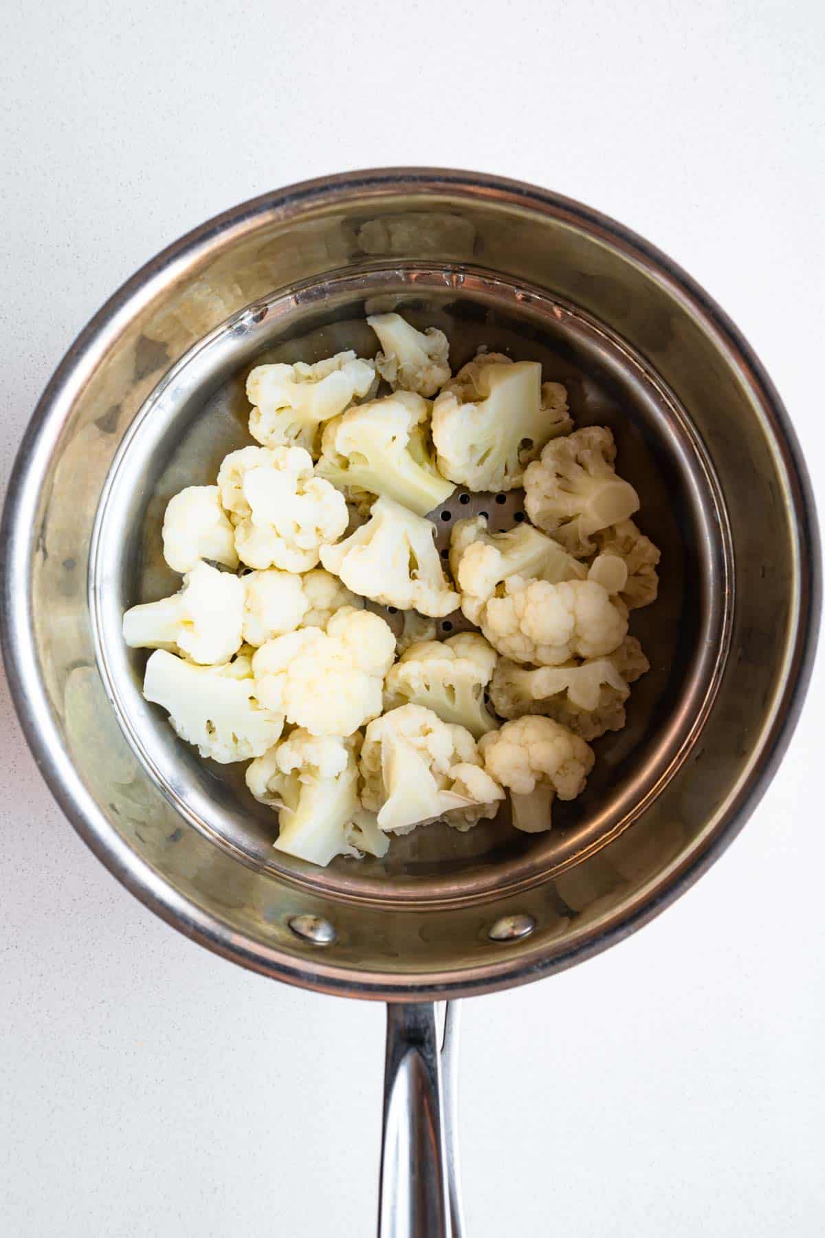 Cauliflower florets in a steaming basket.