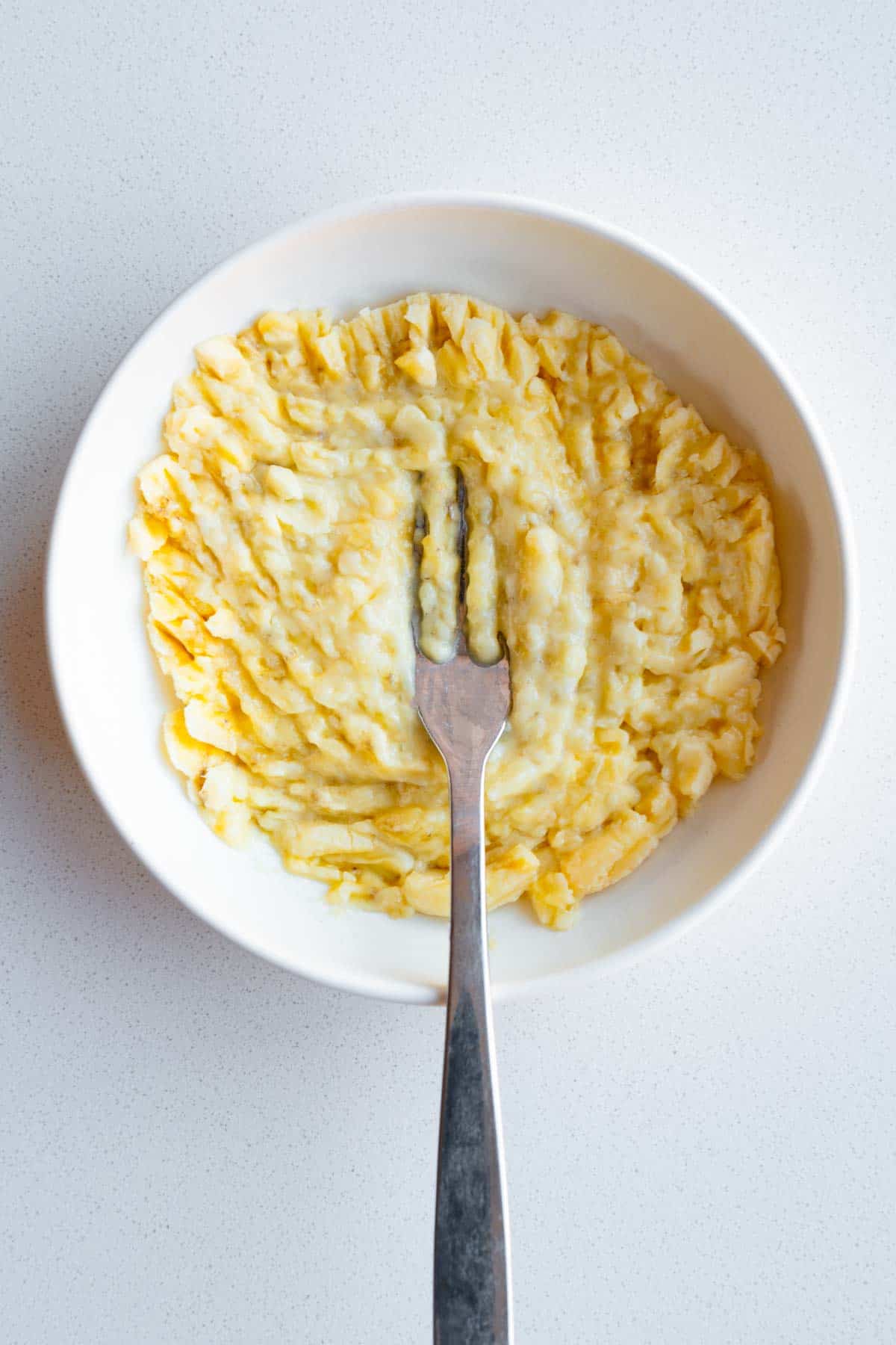 Mashed banana in a white bowl.