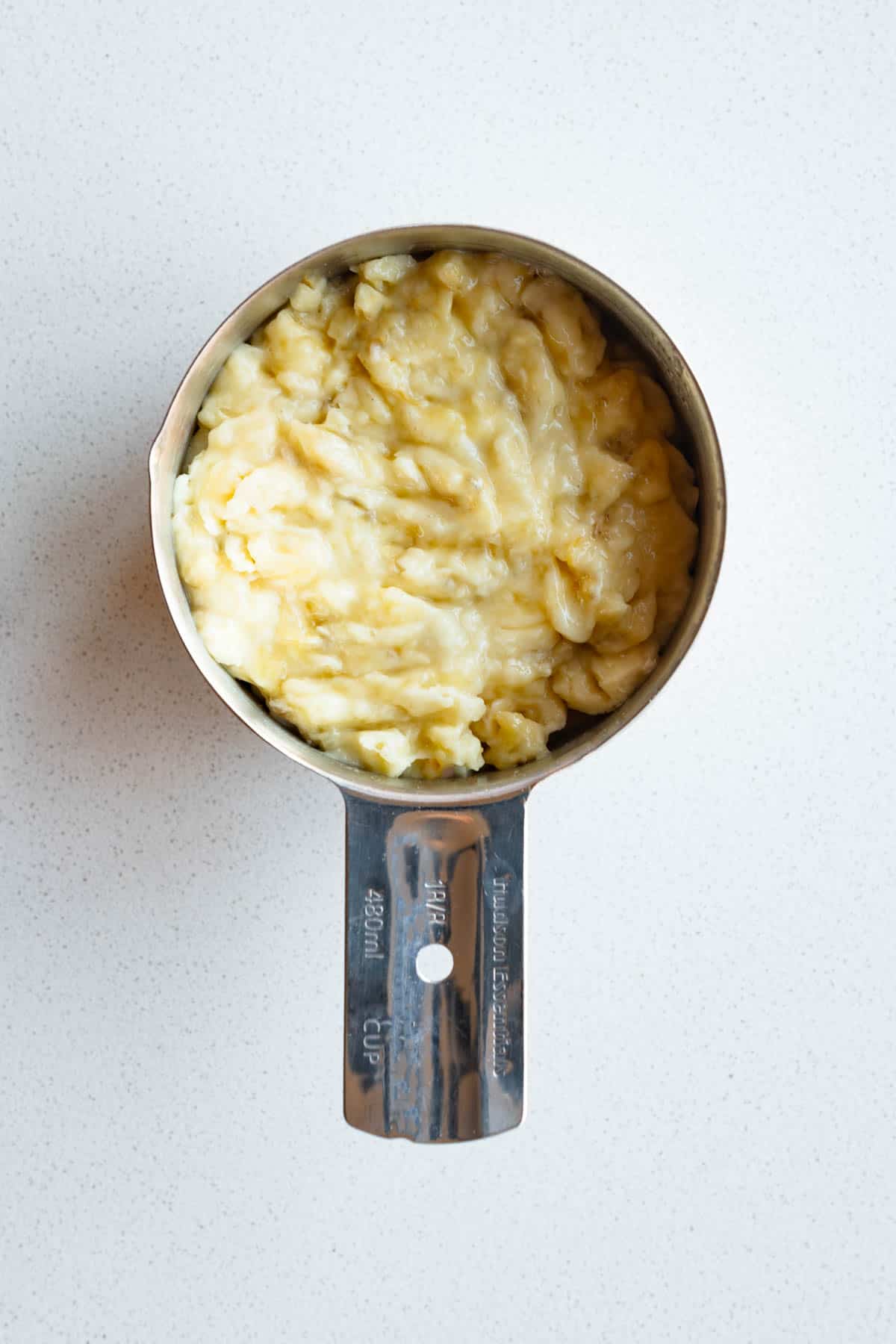 Mashed bananas in a measuring cup.