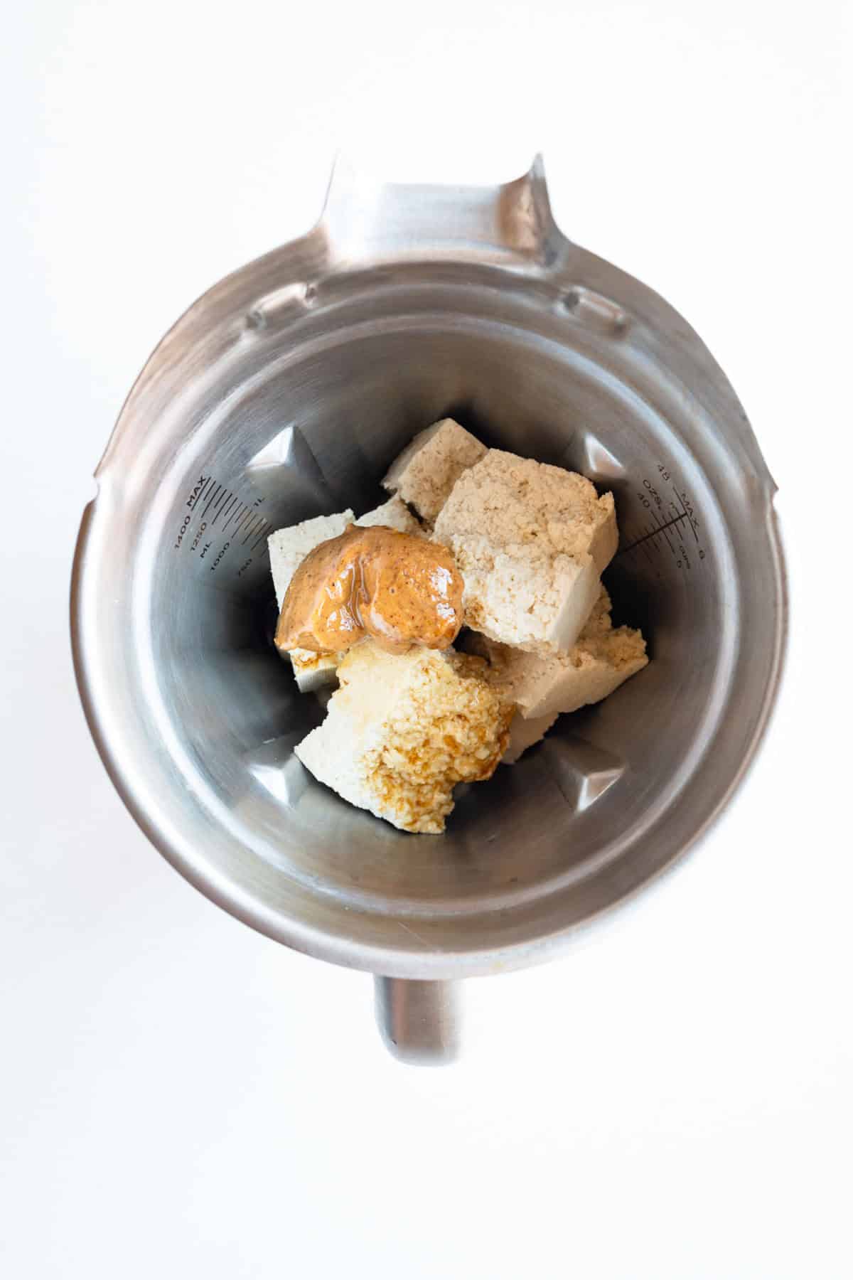 Tofu, nut butter, vanilla, nondairy milk, soaked dates, and mashed banana in a blender.
