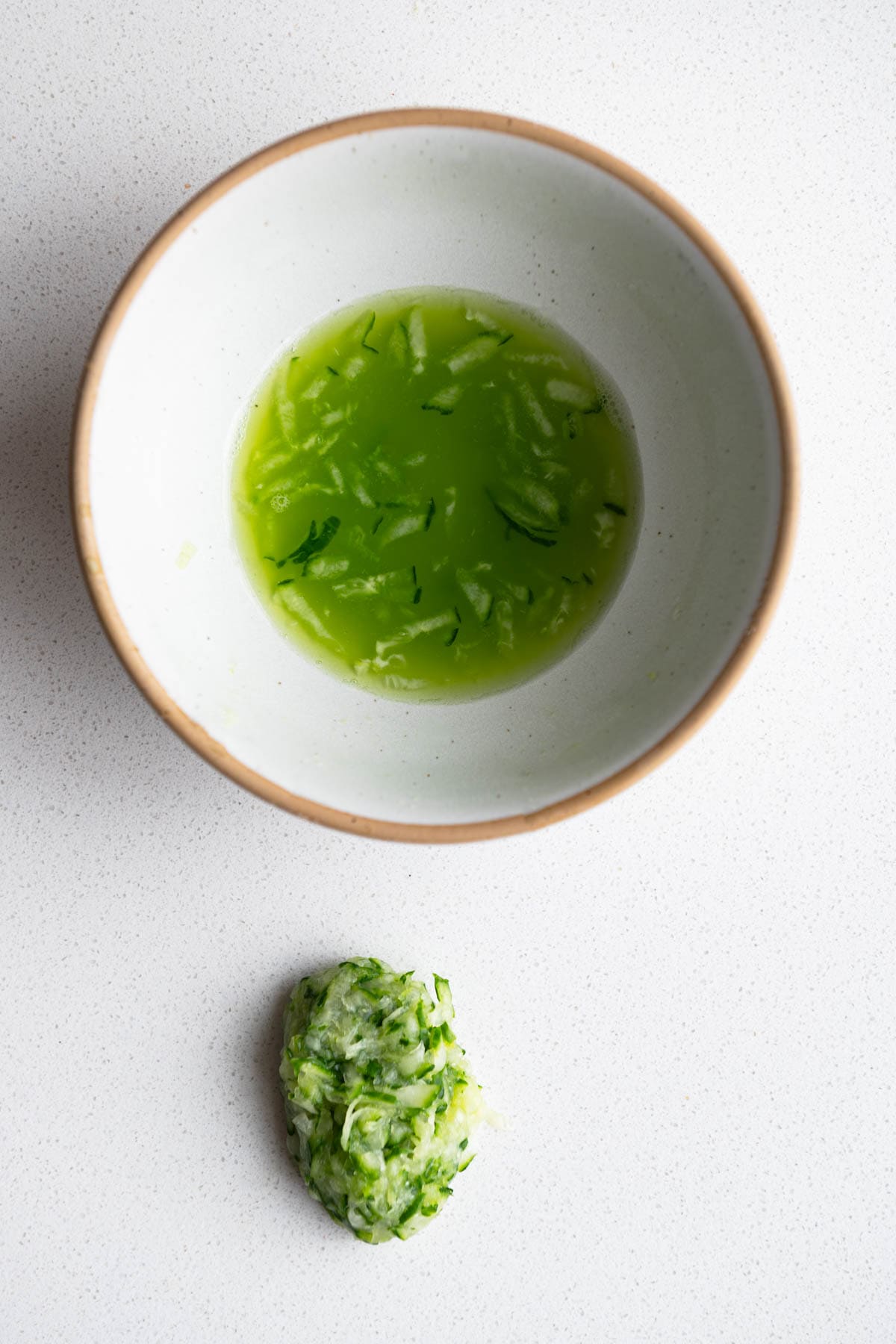 Squeezed cucumber with the juice in a bowl.