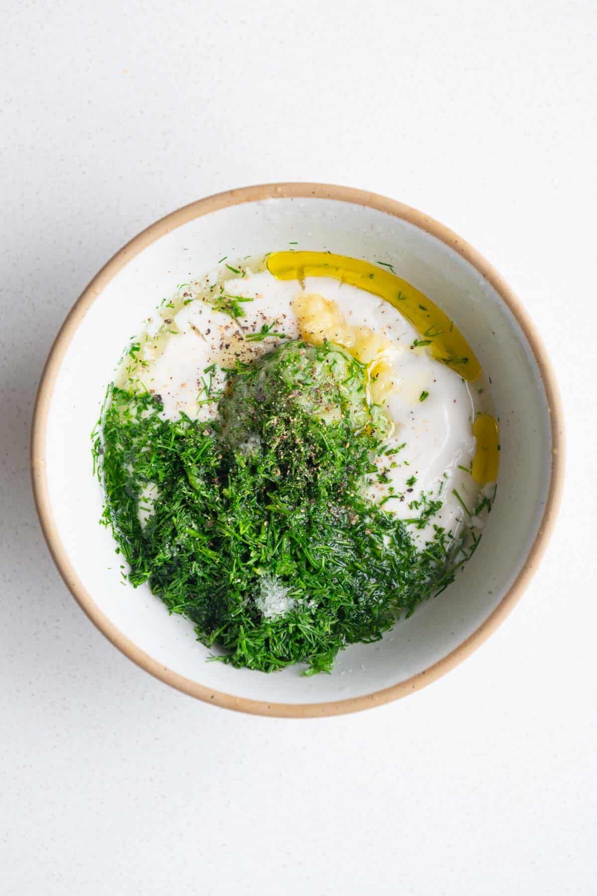 Nondairy yogurt, dill, lemon juice, mustard and garlic in a bowl.