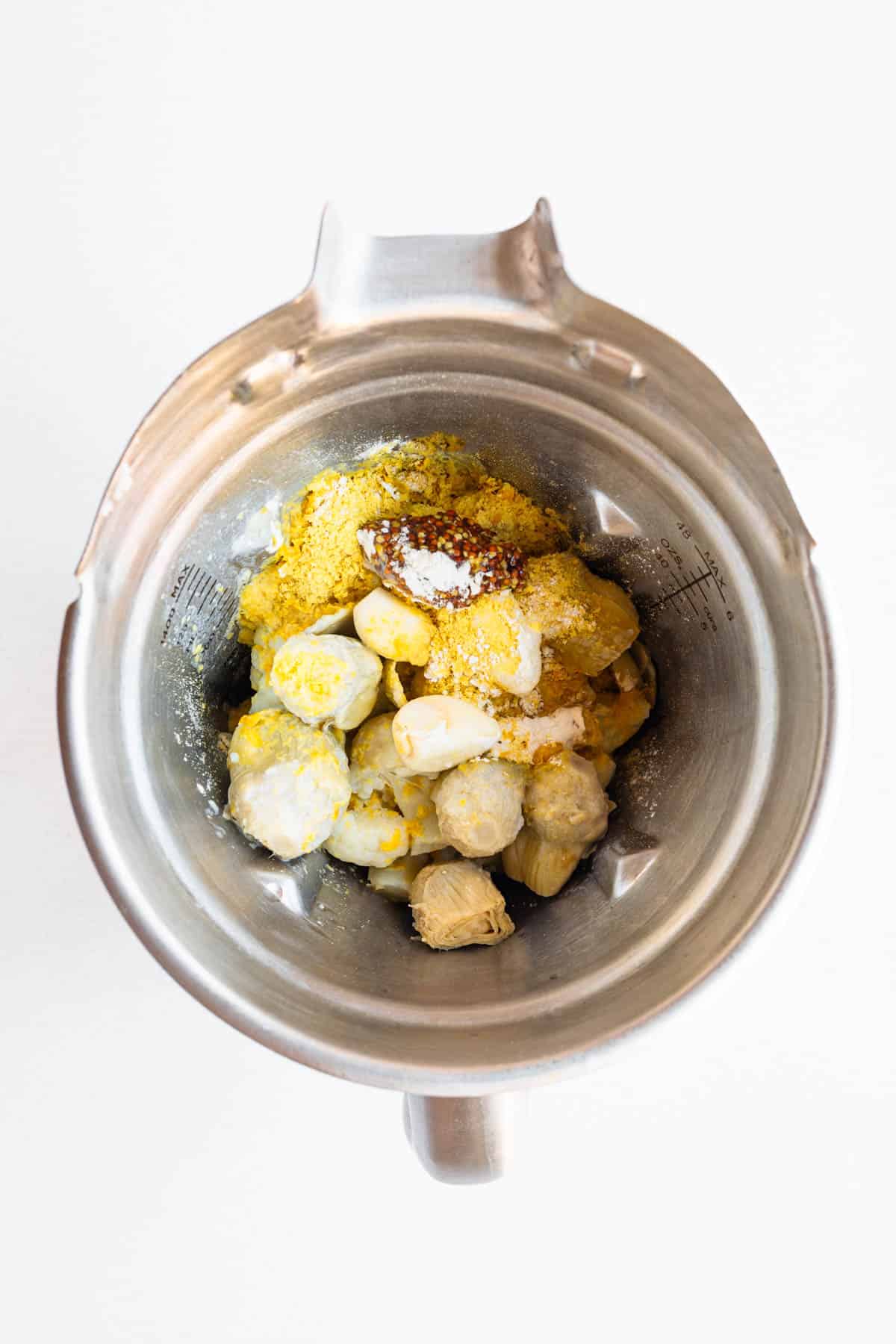 Cauliflower florets, artichoke hearts, fresh herbs, garlic, onion powder, nutritional yeast, and mustard in a blender.