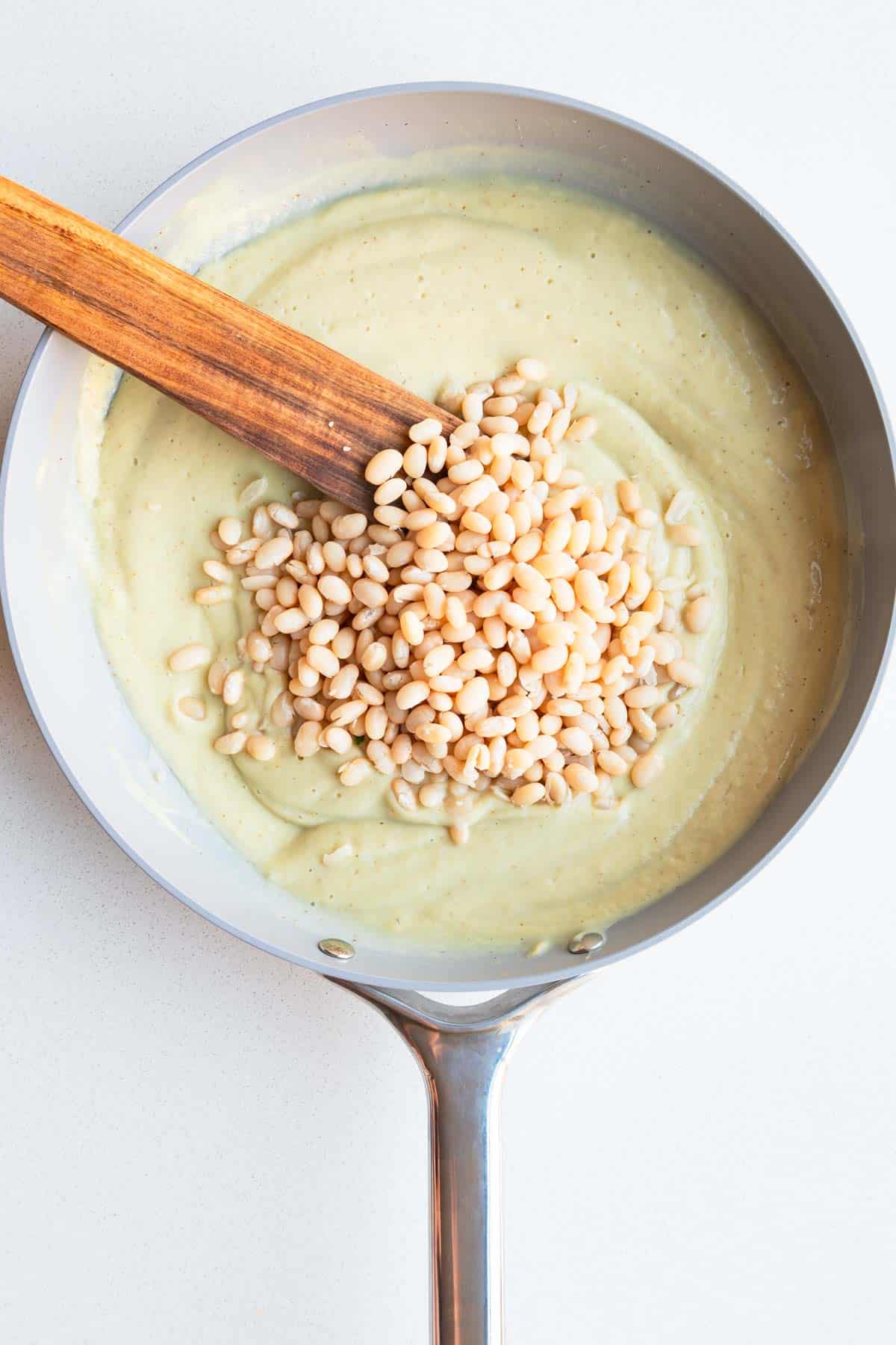 Cauliflower cream sauce in a skillet topped with white beans.