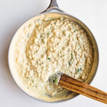 White beans in cauliflower cream sauce in a skillet.