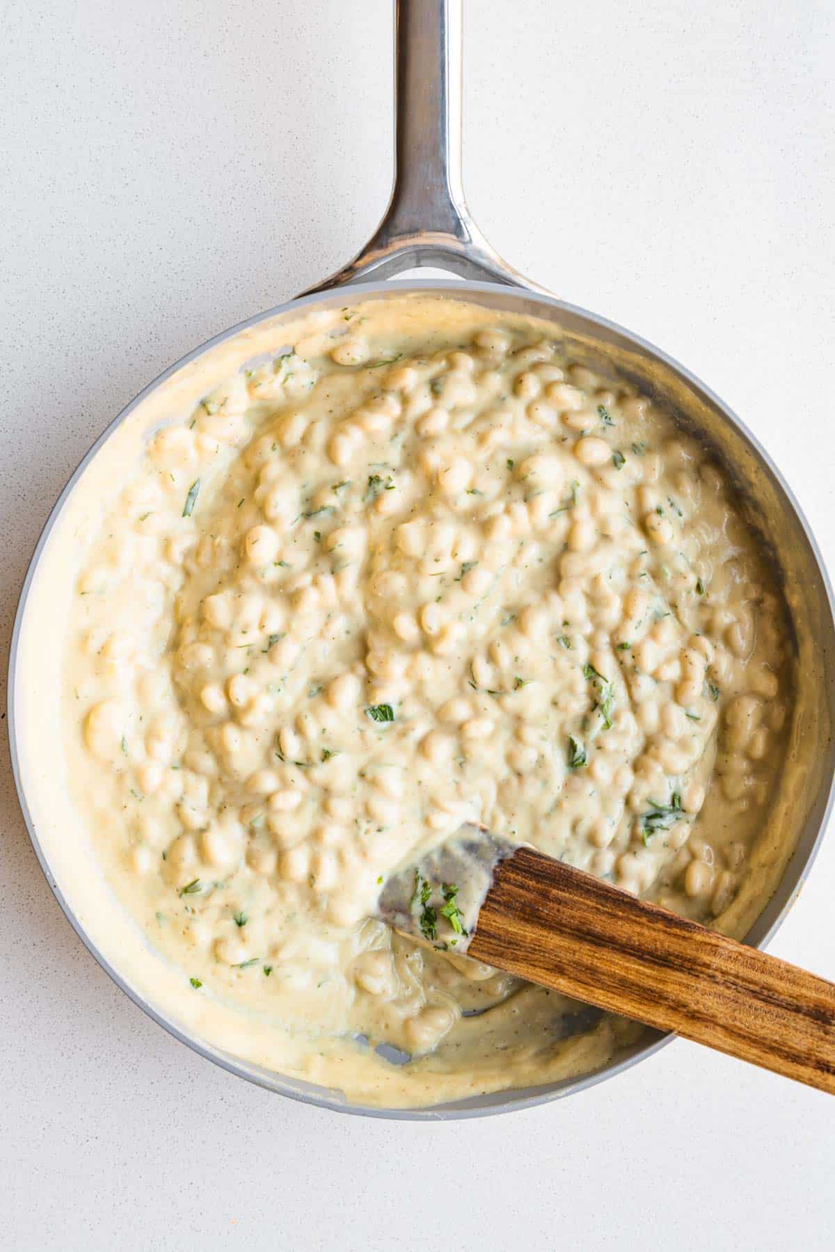 White beans in cauliflower cream sauce in a skillet.